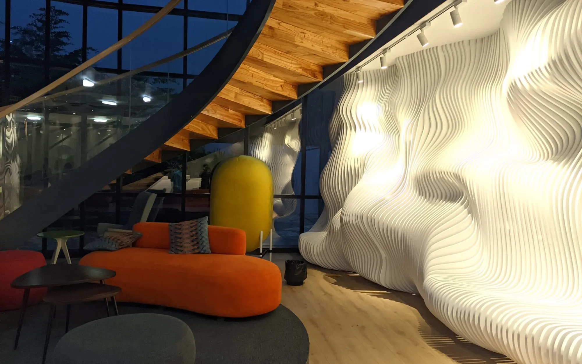 Designer interior with a sculpted wall, spiral stair and orange sofa