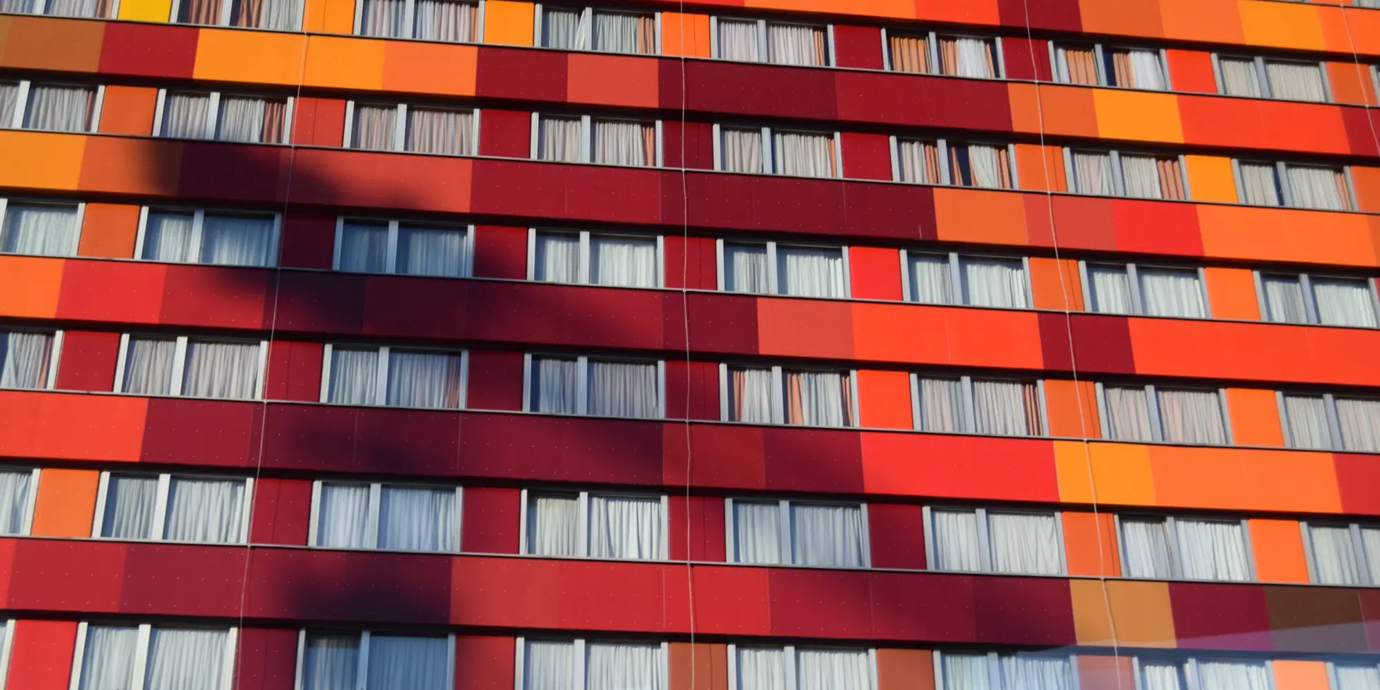Facade of a building clad in red and orange panels